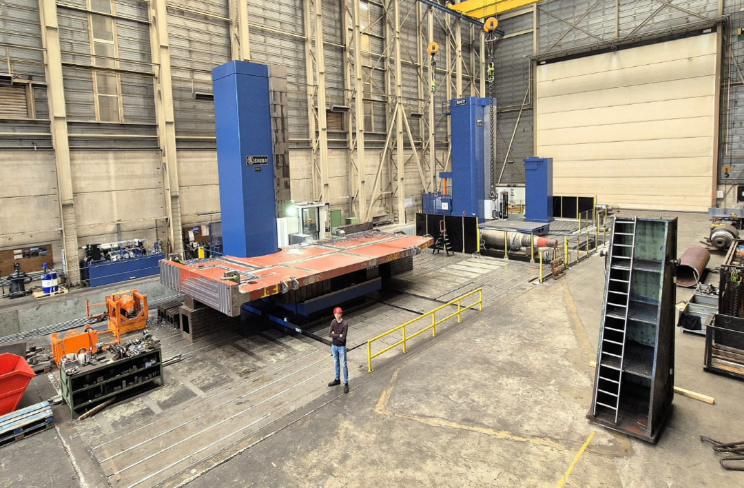 Niek Breman bij de duo-kotterbank. Links is de twintig jaar oude kotterbank te zien die in dezelfde kleuren is gespoten als de nieuwe SMT HCW 3000. Samen kunnen ze over een afstand van 40 meter simultaan aan één werkstuk of afzonderlijk aan meerdere werkstukken bewerken.